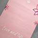 Close-up of the Compact Love and Life pink suede yoga mat featuring inspirational typography.
