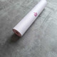Rolled white suede TPE yoga mat with purple flower design on a grey stone background