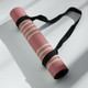 Rolled pink Deco yoga mat secured with a black carry strap for easy transport