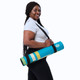 Woman carrying the rolled Retro Pathway yoga mat with a shoulder strap
