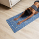 Woman practising yoga on a blue Art Deco patterned yoga mat in a bright studio