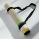 Rolled neutral retro stripe yoga mat secured with a black carry strap