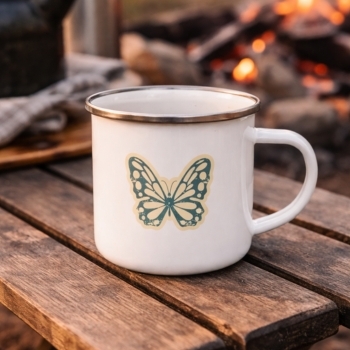 “Butterfly design enamel mug on wooden table, outdoor setting