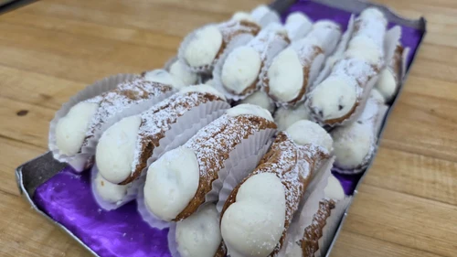 Small cannoli filled with ricotta cream, dusted with powdered sugar