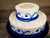 Approximate Servings 40. Sizes 7" & 12". Two tiered cake with ribbon wrapping around both tiers and a pipped deco on front and top sides.
