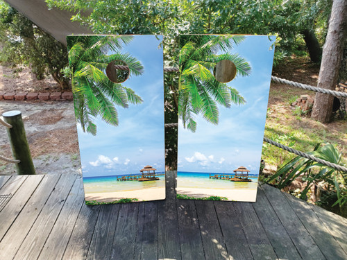 A scenic beach with a beach hut in the distance on a set of cornhole boards
