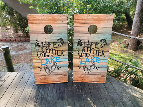 "Life is Better at the Lake Cornhole Boards featuring rustic lake scene with wooden dock, calm water, and relaxing outdoor theme"