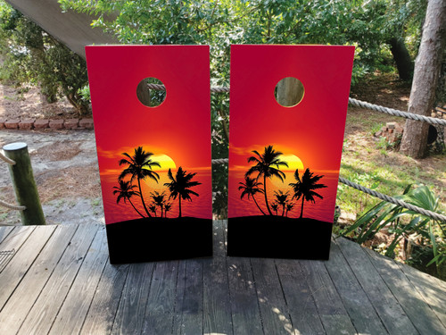 cornhole boards featuring a red beach sunset and palm trees