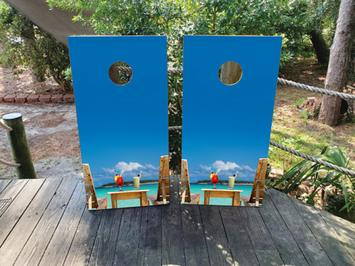 cornhole boards featuring beach chairs with drinks on the arm rests, overlooking the ocean
