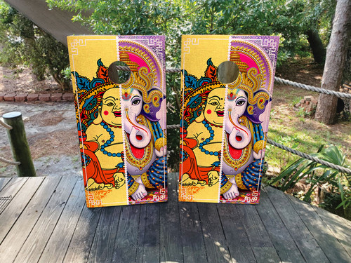 Pair of vibrant cornhole boards featuring a colorful artistic depiction of Lord Ganesha, with bold yellows, purples, reds, and intricate patterns creating a spiritual and cultural aesthetic.