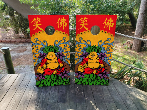 Pair of colorful cornhole boards featuring a cheerful Laughing Buddha surrounded by vibrant lotus flowers, with bold red and yellow background and Chinese characters above.