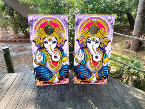 Pair of cornhole boards featuring a colorful and highly detailed illustration of Lord Ganesha with a radiant halo, adorned in ornate traditional clothing and surrounded by purple and pink lotus elements.