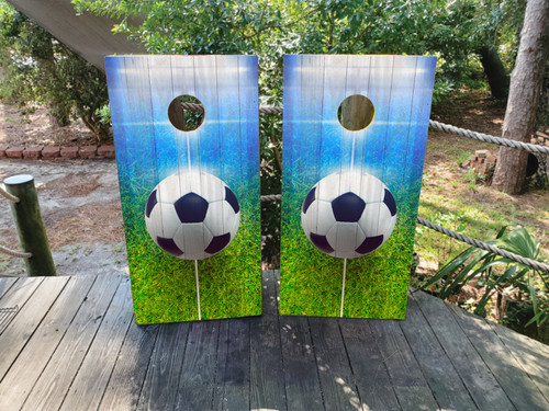 Cornhole boards featuring a soccer ball on a soccer field