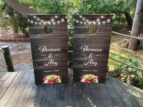 Custom wedding cornhole boards in a rustic or country theme featuring barnwood and flowers and lights