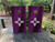 A cornhole set featuring a zia symbol on a purple background
