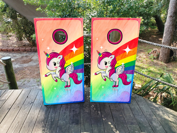 A colorful rainbow and unicorn on cornhole boards