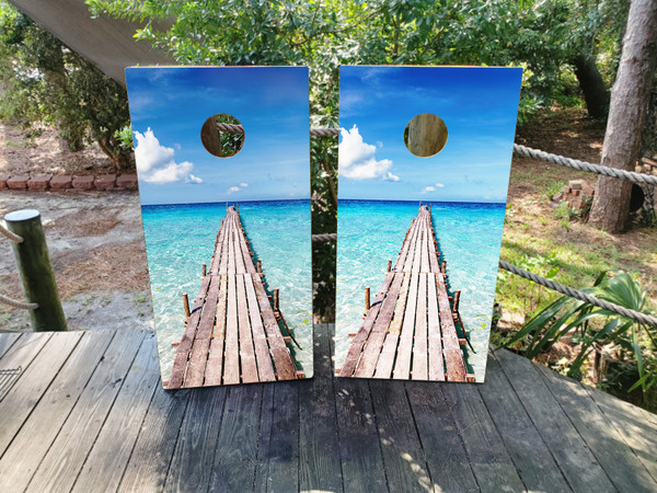 cornhole boards featuring a beach deck going out to bright blue water