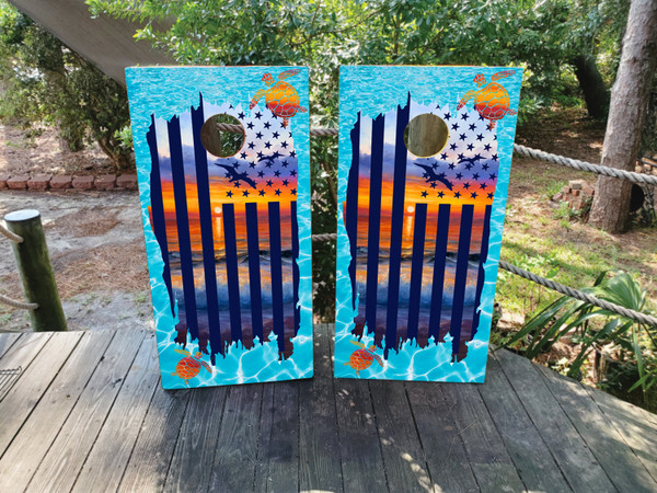 "Beach USA Flag Cornhole Boards featuring American flag overlay on tropical beach scene with palm trees and ocean waves"