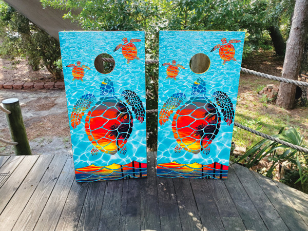 Cornhole boards featuring a beach scene behind a  turtle