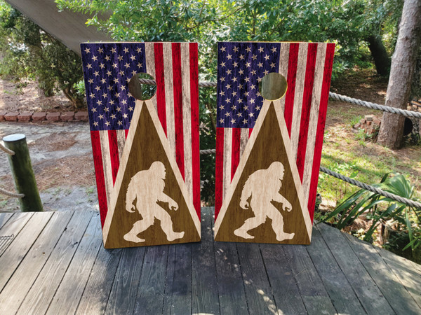 cornhole boards featuring big foot on a wood grain texture with a USA flag on top