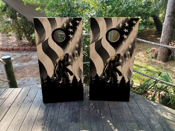 cornhole boards featuring big foot in the woods on a wood grain texture with a USA flag