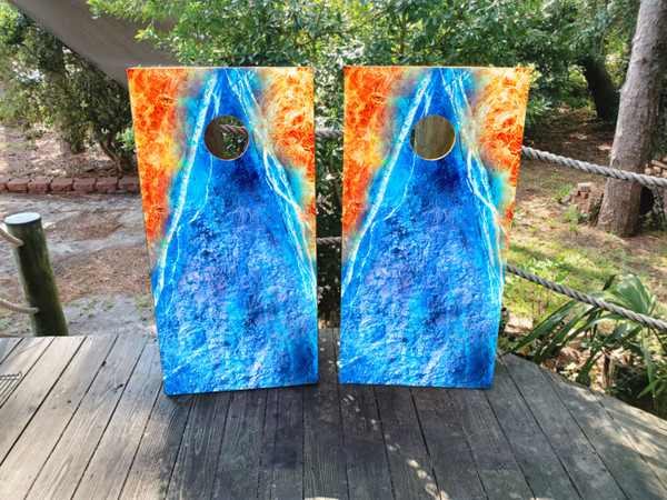 Pair of vivid cornhole boards featuring a bold fire and ice design, with swirling flames on the top left and icy textures flowing down through the center and bottom right in a mirrored triangle formation.