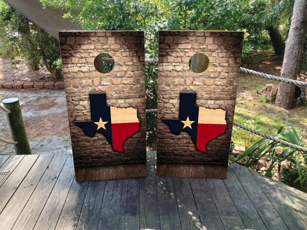 Cornhole boards featuring the state of texas on a brick wall