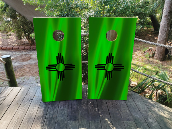 A cornhole set featuring a zia symbol on a green background