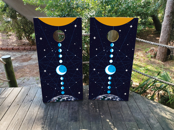 Pair of cornhole boards featuring moon phases aligned vertically over a starry galaxy background, with Earth at the bottom and a golden sun crescent at the top, creating a celestial balance.