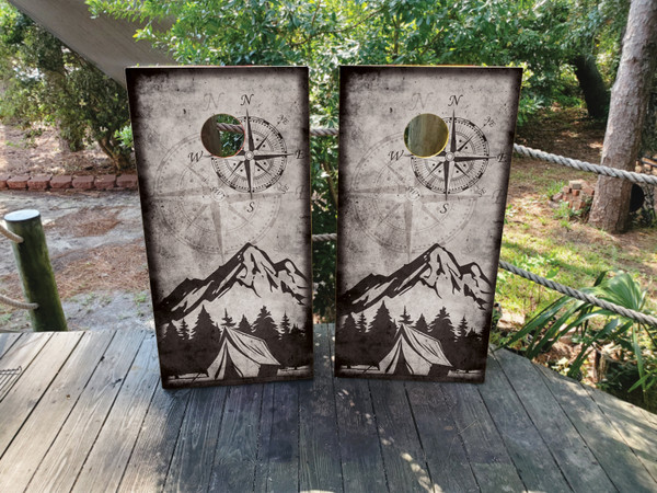 cornhole boards featuring a campsite in the mountains with a compass