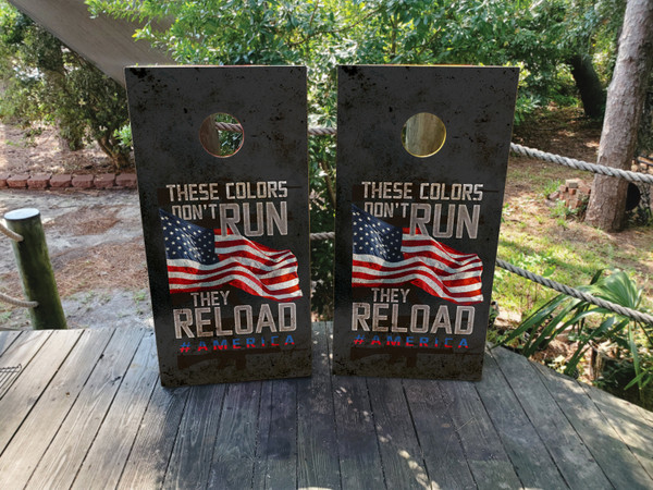 cornhole boards featuring an American flag with the text These Colors Don't Run, They Reload #America