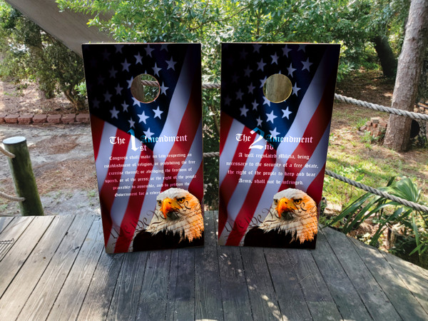 Cornhole boards featuring a bald eagle and a USA/American flag background. On one board is the 1st amendment, on the other board is the 2nd amendment.