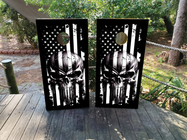 Pair of cornhole boards featuring a bold black and white American flag background with a menacing skull graphic in the center, creating a stark and powerful monochrome aesthetic.