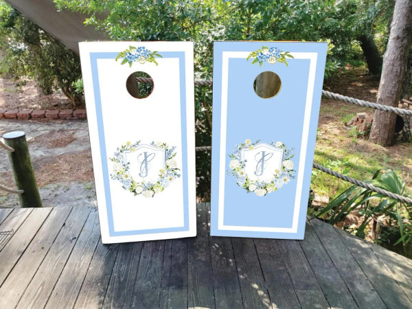 blue and white wedding cornhole boards featuring a custom wedding crest
