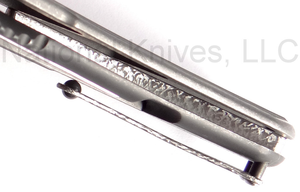 Todd Begg Knives Bodega 2.0 folding knife with flipper tab - shown close up of back spacer.  2-tone N690 stainless steel plain edge blade.  Gray titanium handle.
For reference only.