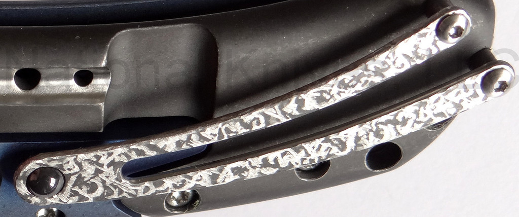 Todd Begg Knives Bodega 2.0 folding knife with flipper tab - shown close up of pocket clip.  2-tone N690 stainless steel plain edge blade.  Blue titanium handle.
For reference only.