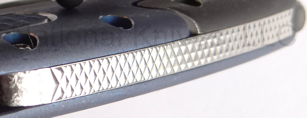 Todd Begg Knives Bodega 2.0 folding knife with flipper tab - shown close up of back spacer.  2-tone N690 stainless steel plain edge blade.  Blue titanium handle.
For reference only.