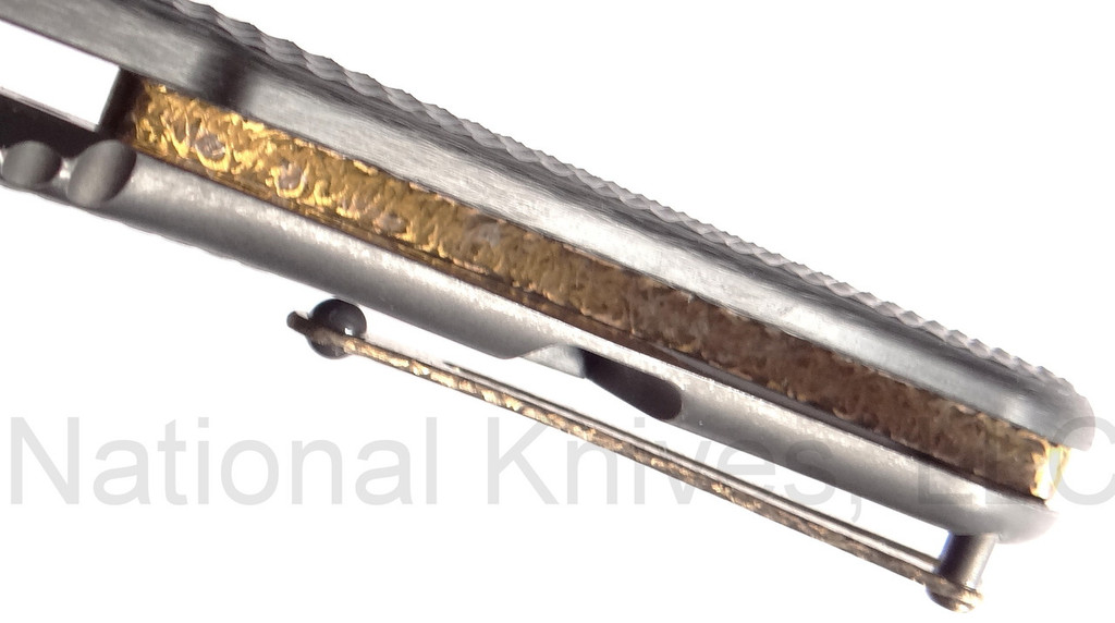 Todd Begg Knives Bodega Field Grade folding knife with flipper tab - shown close up of back spacer.  2-tone N690 stainless steel plain edge blade.  Carbon fiber handle.
For reference only.