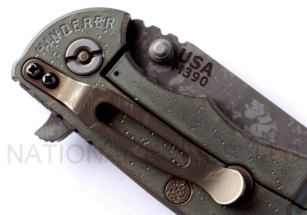 Rick Hinderer Knives Battlefield Pick Up XM-18 3.5" Harpoon Spanto folding knife with thumb stud and flipper tab - close up of lock side pivot shown.  M390 stainless steel plain edge blade.  OD green G-10 handle with titanium lock side.  Model K25520SP00.
For reference only.