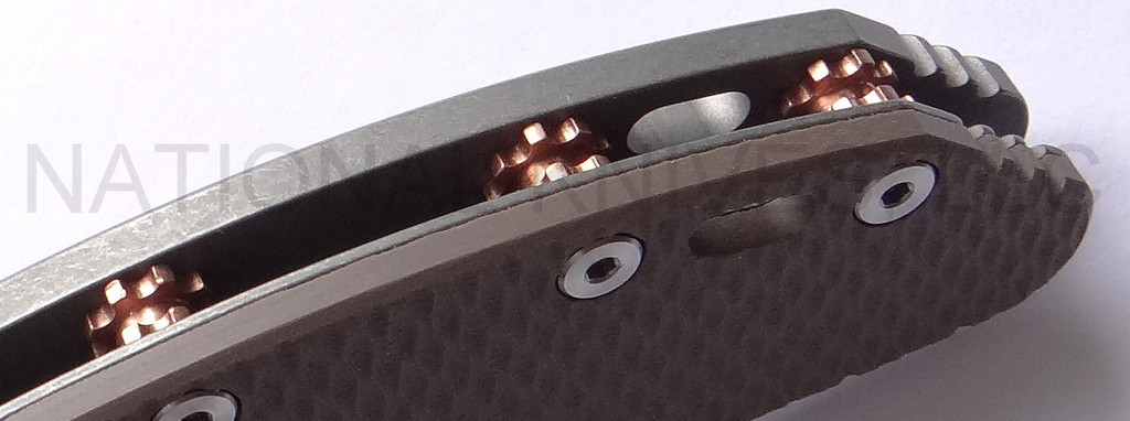 Rick Hinderer Knives Gearhead XM-24 Wharncliffe folding knife with thumb stud and flipper tab - close up of standoffs.  Working Finish M390 stainless steel plain edge blade.  FDE G-10 handle with Working Finish lock side.  Model K3023SGW00.
For reference only.