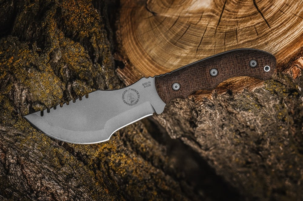 TOPS Knives 20th Anniversary Tom Brown Tracker fixed blade knife - shown out of sheath reverse.  S35VN stainless steel plain edge blade.  Brown Burlap Micarta handle.  Model TBT-032.
For reference only.