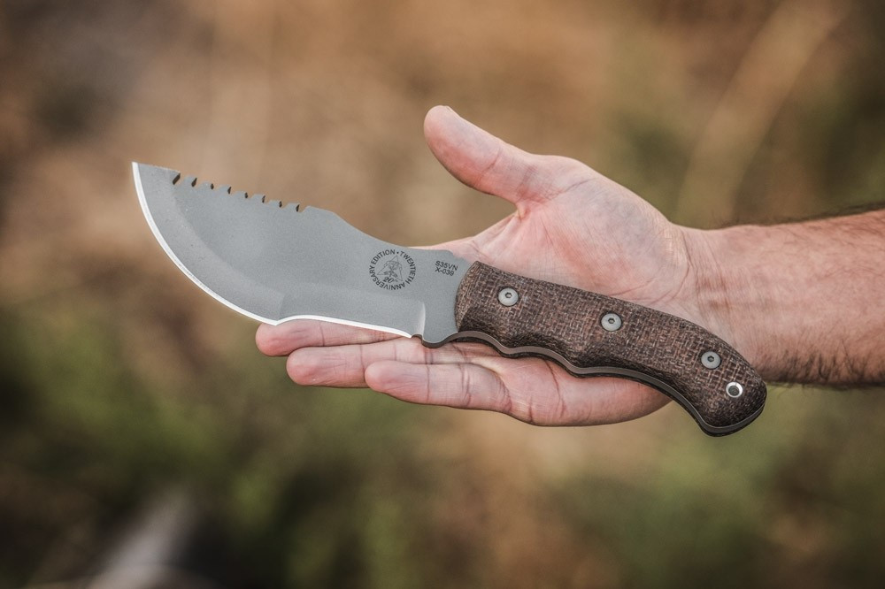 TOPS Knives 20th Anniversary Tom Brown Tracker fixed blade knife - shown out of sheath and in hand reverse.  S35VN stainless steel plain edge blade.  Brown Burlap Micarta handle.  Model TBT-032.
For reference only.
