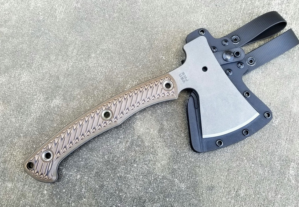 RMJ Tactical Little Bird 18 camp style axe - shown out of sheath obverse with sheath in background.  Tungsten Cerakote 52100 steel plain edge head.  Hyena Brown G-10 handle.
For reference only.