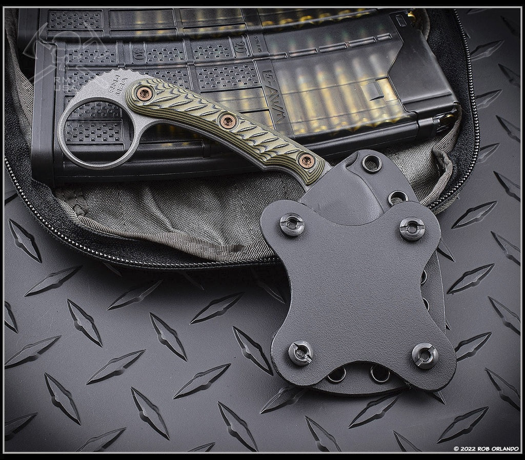 RMJ Tactical Korbin Karambit fixed blade knife - shown in sheath reverse.  Tungsten Cerakote Nitro-V stainless steel plain edge blade.  Dirty Olive G-10 handle.  Model K-KO-TU-DO.