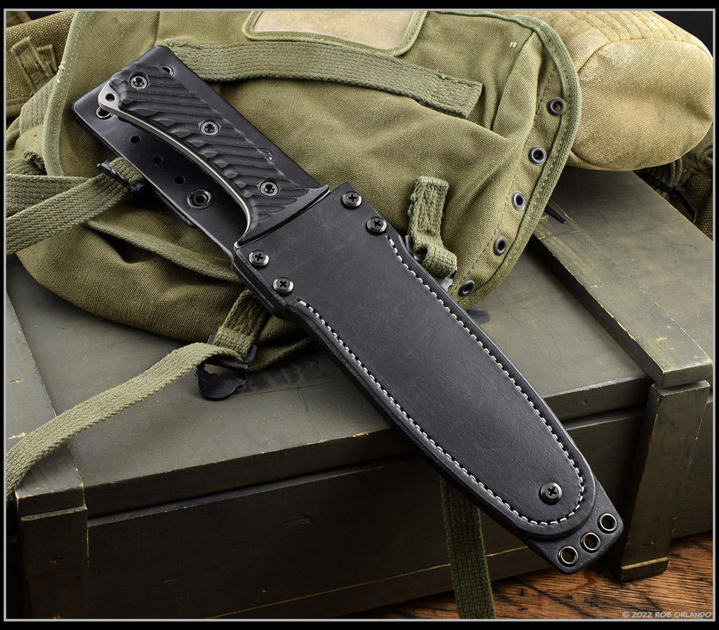 RMJ Tactical National Knives, LLC Exclusive 3V Syndicate Jungle Combat fixed blade knife - shown in sheath obverse.  Urban Camo colored 3V steel plain edge blade.  Black G-10 handle.  Model K-JC-3V-UC.
For reference only.