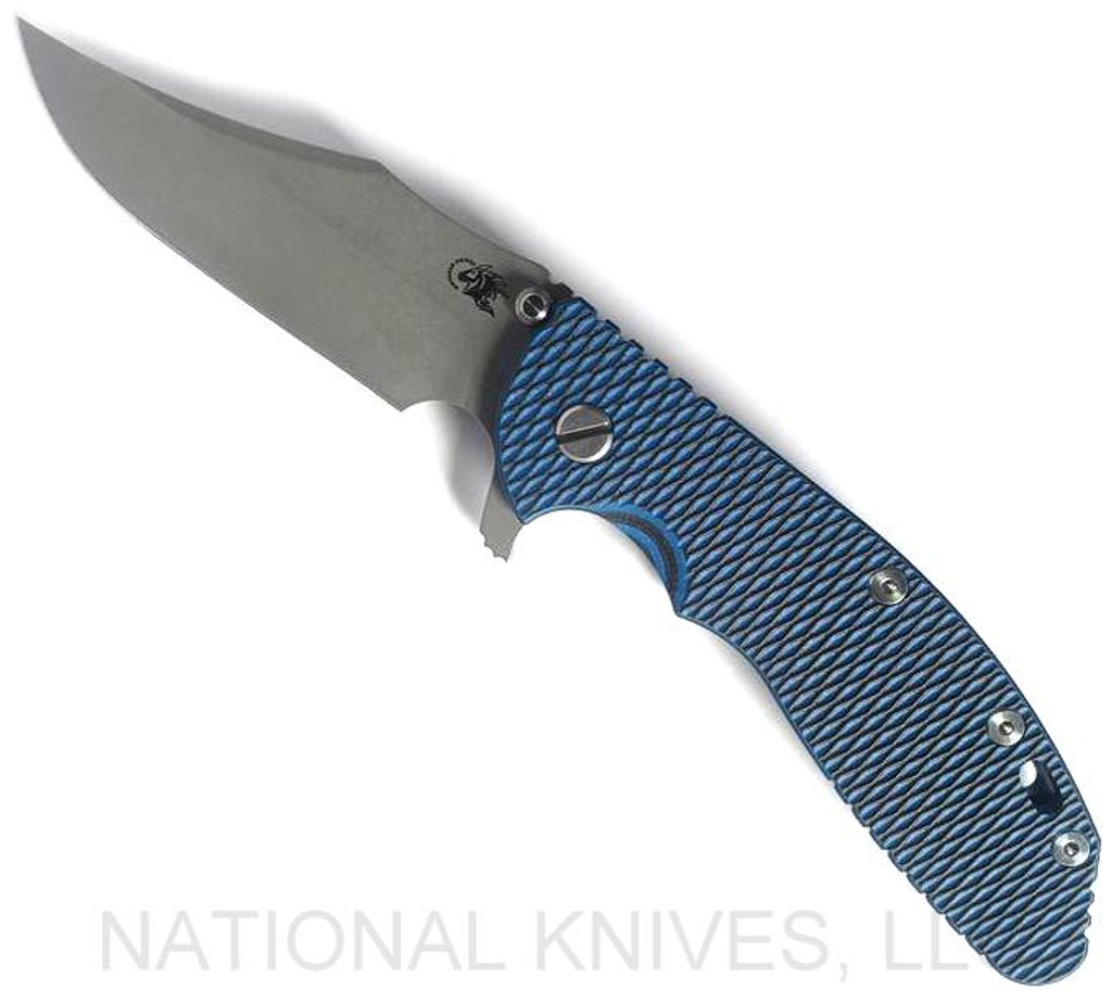 Rick Hinderer Knives XM-24 Bowie folding knife with thumb stud and flipper tab - shown open presentation side.  Working Finish 20CV stainless steel plain edge blade.  Blue - black G-10 handle with Battle Blue lock side.  Model KXM40BO.
