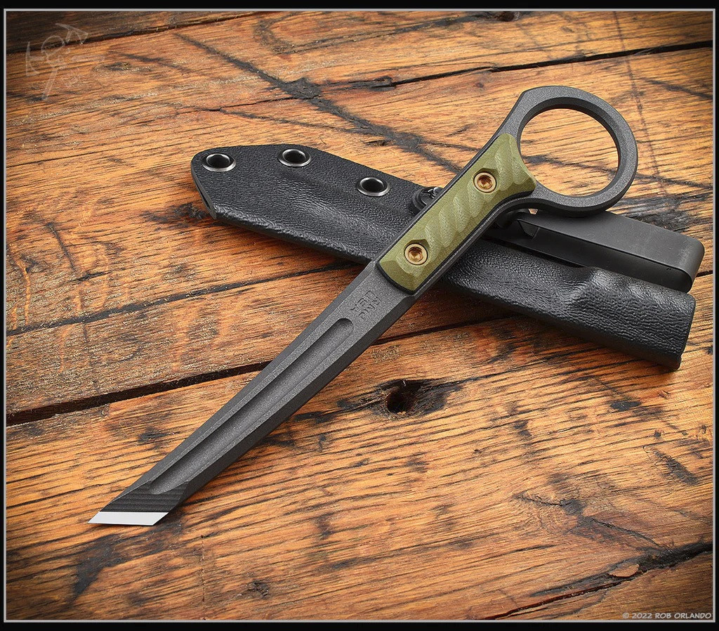 RMJ Tactical Stabby Guy multitool - shown out of sheath reverse with sheath in background.  Cobalt Cerakote CPM-3V steel construction with OD green G-10.