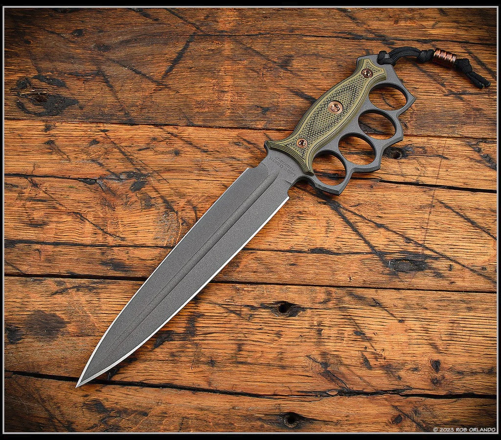 RMJ Tactical Lady Death fixed blade knife - shown out of sheath reverse.  Cobalt Cerakote MagnaCut stainless steel plain edge blade.  Dirty Olive G-10 handle.  Model K-LD-MC-CO-DO-BG.