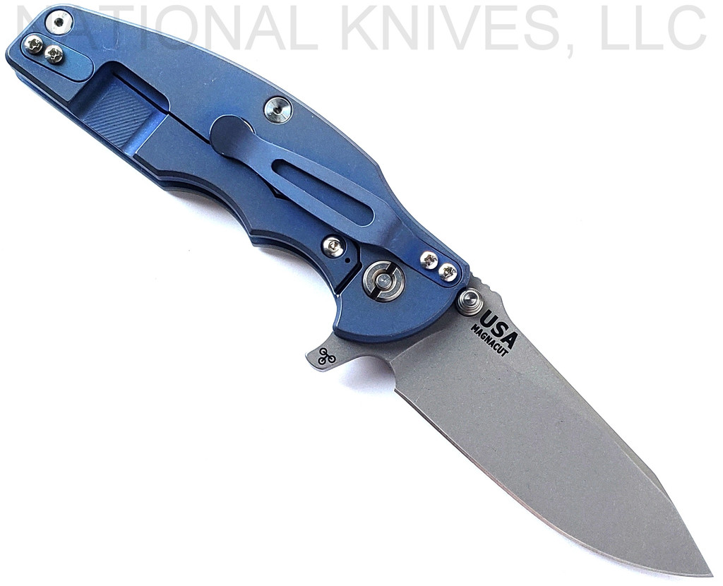 Rick Hinderer Knives Jurassic Hollow Grind Slicer folding knife with flipper tab - shown open lock side.  Working Finish MagnaCut stainless steel plain edge blade.  Translucent Green G-10 handle scale with Battle Blue titanium lock side.  Model KJURSLHO.