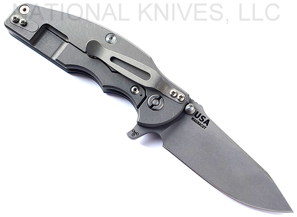 Rick Hinderer Knives Jurassic Hollow Grind Slicer folding knife with flipper tab - shown open lock side.  Working Finish MagnaCut stainless steel plain edge blade.  Blue - Black G-10 handle scale with Working Finish titanium lock side.  Model KJURSLHO.